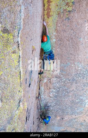 Un alpinista maschile sale su una ripida parete rocciosa nelle Dragoon Mountains, Cochise Stronghold, Arizona Foto Stock