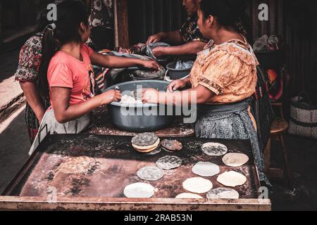 Donne guatemalteche e maya che producono tortillas in modo tradizionale sul mercato a Chichicastenango, Guatemala Foto Stock