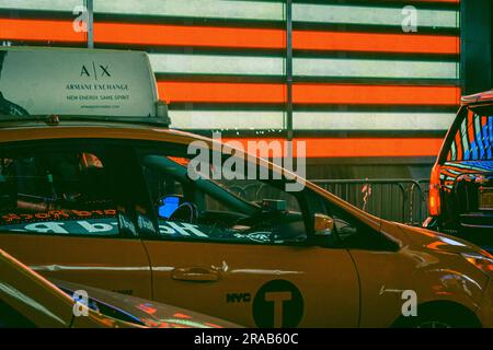 Una bandiera americana illuminata si riflette in un veicolo di passaggio a Times Square. Foto Stock