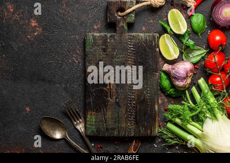 Cucina vegana. Verdure fresche, funghi, spezie ed erbe aromatiche con tagliere su pietra nera Foto Stock