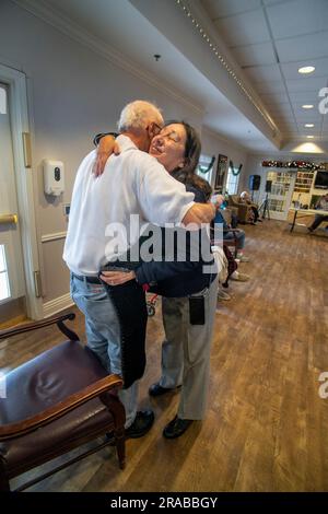 Con un abbraccio, un volontario ispanico membro di un gruppo di maglieria della chiesa cattolica distribuisce il loro lavoro a una casa di cura anziana residente a San Juan, California Foto Stock