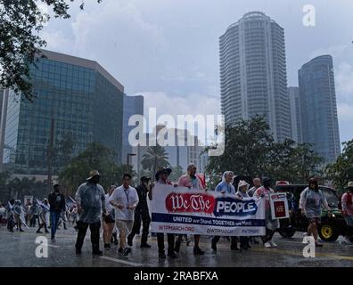 Piedi Lauderdale, Florida, USA. 2 luglio 2023. I manifestanti marciano per le strade del centro di Fort Lauderdale, in Florida, sotto la pioggia durante la marcia nazionale "We the People". Nonostante il tempo inclemente, diverse migliaia di persone si sono rivelate per l'evento. La marcia fu messa in scena nel centro di Fort Lauderdale, in Florida, il 2 giugno 2023. L'evento si è concentrato sull'erosione della democrazia, sul controllo delle armi, e soprattutto in Florida, sui recenti attacchi alle libertà delle persone gay e transgender. La protesta è stata organizzata dalla AIDS Healthcare Foundation, insieme a oltre 50 organizzazioni partner e moneta Foto Stock