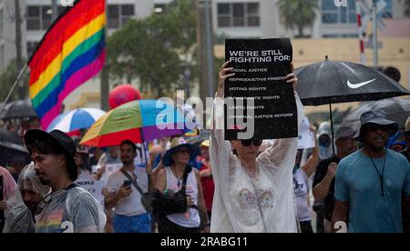 Piedi Lauderdale, Florida, USA. 2 luglio 2023. Una donna tiene un cartello di protesta mentre i manifestanti marciano per le strade del centro di Fort Lauderdale, Florida sotto la pioggia. Nonostante il tempo inclemente, diverse migliaia di persone si sono rivelate per l'evento. Il We the People National March è stato messo in scena nel centro di Fort Lauderdale, Florida, il 2 giugno 2023. L'evento si è concentrato sull'erosione della democrazia, sul controllo delle armi, e soprattutto in Florida, sui recenti attacchi alle libertà delle persone gay e transgender. La protesta è stata organizzata dalla AIDS Healthcare Foundation, insieme a oltre 50 organizzazioni partner Foto Stock