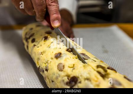 Produzione di un originale Dresda Christstollen a Dresda, Germania. Il rotolo di impasto viene tagliato con un coltello lungo e profondo circa 1 cm Foto Stock