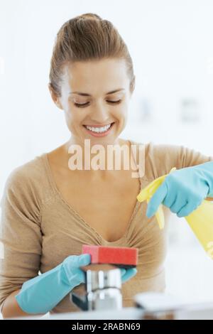 Felice giovane casalinga pulizia in bagno Foto Stock