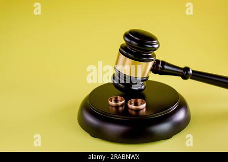 Primo piano di anelli di nozze su mazzuolo di legno a tavola nelle aule di tribunale Foto Stock
