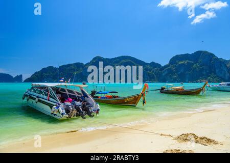 KRABI, THAILANDIA - MARZO 2018: Barche tradizionali a coda lunga in legno e barche a motore su una spiaggia di sabbia bianca con acqua marina azzurra sull'isola di Ko Phi Phi Don su un su Foto Stock