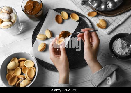 Donna che prepara deliziosi biscotti a forma di noce al tavolo di legno bianco, sopra la vista Foto Stock