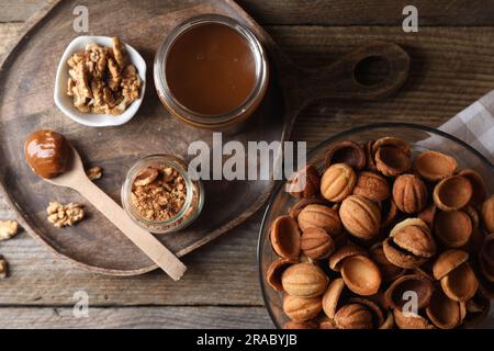 Preparare biscotti a forma di noce. Impasto cotto, latte condensato caramellato e noci su tavola di legno, piatto Foto Stock