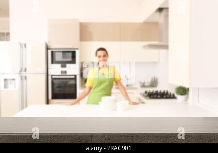 Donna felice con piatti puliti in cucina, concentrati sul tavolo vuoto Foto Stock