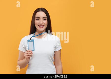 Happy Woman con badge vip Pass su sfondo arancione. Spazio per il testo Foto Stock