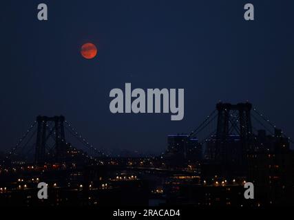 New York, Stati Uniti. 2 luglio 2023. Un Buck Supermoon quasi pieno sorge dietro il Williamsburg Bridge e il quartiere di Brooklyn domenica 2 luglio 2023 a New York City. La superluna di domani segnerà il primo di quattro superlune quest'anno. Foto di John Angelillo/UPI Credit: UPI/Alamy Live News Foto Stock