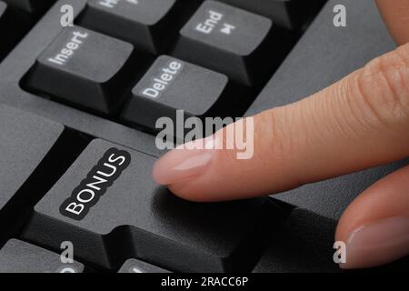 Donna che preme il tasto Bonus sulla tastiera, primo piano Foto Stock