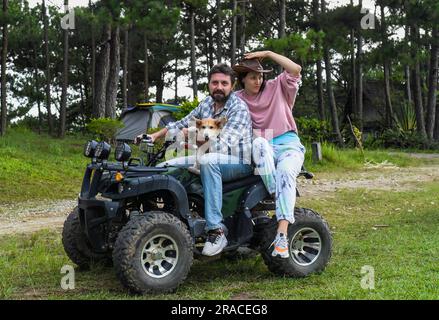 Ritratto di una giovane coppia sposata seduta su un quad nella foresta Foto Stock