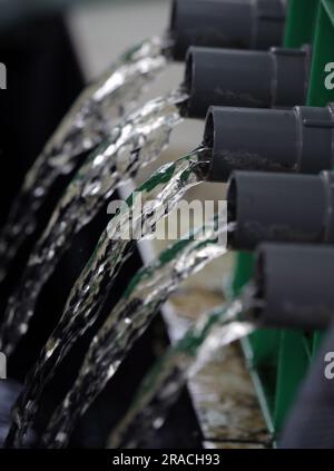 L'acqua fluisce da un tubo. L'acqua pulita fluisce in un tubo dopo essere stata filtrata in uno stagno di pesci Foto Stock