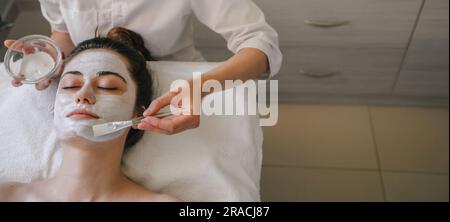 Donna che applica cerotti oculari sul volto del cliente Foto Stock