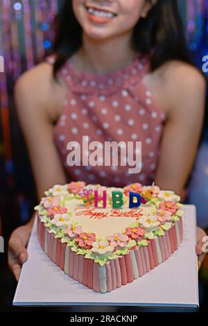 Mano della ragazza che tiene una torta di compleanno concentrati sui momenti felici Foto Stock