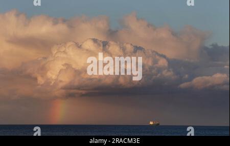 Una nave siede all'orizzonte al tramonto come un arcobaleno si forma al largo della costa vicino alla baia di Cullercoats nel nord-est dell'Inghilterra. Data foto: Domenica 2 luglio 2023. Foto Stock