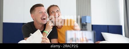 Felice coppia sorridente che registra video a letto sullo smartphone Foto Stock