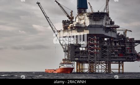 Nave di rifornimento che effettua operazioni di carico con un carro di perforazione con martinetto, piattaforma offshore nel Mare del Nord. Foto Stock