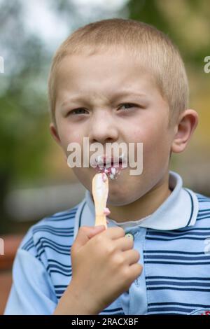 ritratto di un ragazzo che mangia un gelato su una bacchetta da vicino Foto Stock