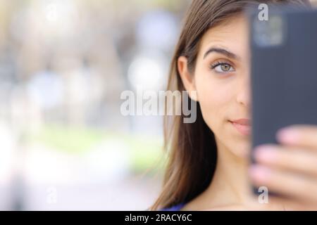 Vista frontale ritratto ravvicinato di una donna sorpresa che controlla il cellulare in strada Foto Stock