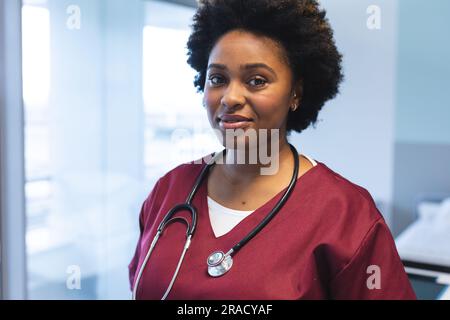 Ritratto di una felice dottoressa afroamericana che indossa scrub e stetoscopio, sorridente. Ospedale, medicina, sanità e lavoro, inalterati. Foto Stock