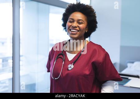 Ritratto di una felice dottoressa afroamericana che indossa scrub e stetoscopio, sorridente. Ospedale, medicina, sanità e lavoro, inalterati. Foto Stock
