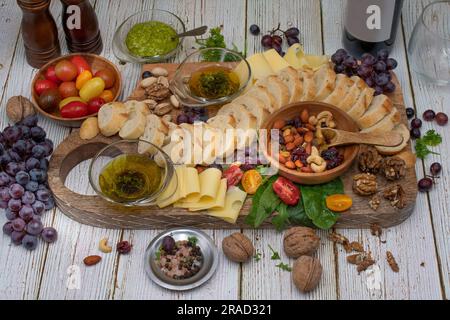 Tavola antipasto con pane, formaggio, noci, olio d'oliva, pomodori e uva Foto Stock