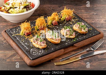 Bruschetta con frutti di mare preparati con sapori asiatici su un tagliere di pietra Foto Stock