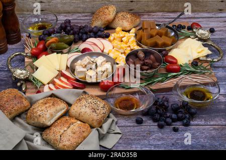 Tagliere di formaggi con frutta, olive, uva e pane Foto Stock