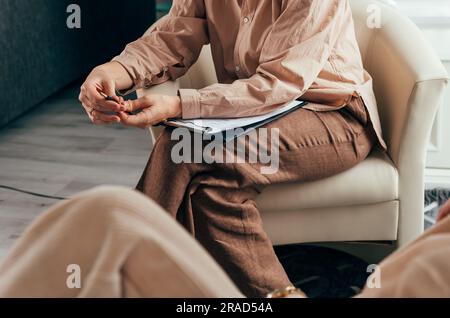 Primo piano delle mani di uno psicologo che scrivono note su un paziente Foto Stock