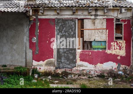 Vecchia casa in rovina in una baraccopoli con facciata deteriorata con finestre chiuse e porte chiuse Foto Stock