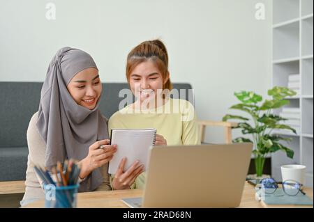 Gruppo di giovani studenti studiano insieme nel loro tempo, donna musulmana che legge con la sua amica. Foto Stock