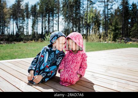 ragazza e ragazzo sedevano vicino ridendo insieme in giardino a casa Foto Stock