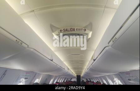 Segnale di uscita di emergenza nel soffitto della cabina dell'aeromobile. Corridoio aereo di linea passeggeri Foto Stock