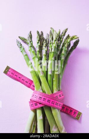 Un fascio di asparagi verdi legato da un nastro a righe rosa Foto Stock