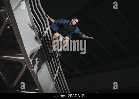 Uomo che pratica il parkour facendo enormi salti spaventosi. Allenamento gratuito degli atleti di running Foto Stock