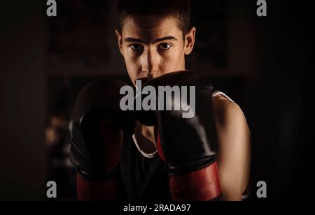 Portarit di giovane pugile di guardia durante l'allenamento in palestra. Foto Stock