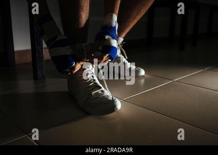 Primo piano sui piedi del pugile che legano le scarpe prima di allenarsi in palestra. Foto Stock