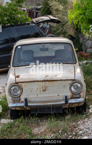 vecchia automobile zastava in un giardino lasciato arrugginire in croazia, automobile zastava abbandonata in un campo. Foto Stock