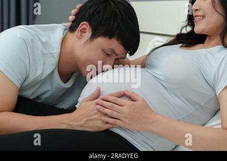 Marito che bacia alla pancia della moglie incinta Foto Stock