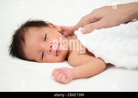 mano di madre che mette il suo bambino felice appena nato su un letto Foto Stock