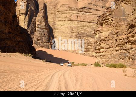 Wadi Rum, Giordania - 19 dicembre 2022: Un convoglio di veicoli fuoristrada con i turisti si dirige verso Wadi Rum nella parte giordana del deserto arabo. Foto Stock