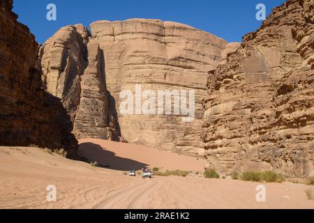 Wadi Rum, Giordania - 19 dicembre 2022: Un convoglio di veicoli fuoristrada con i turisti si dirige verso Wadi Rum nella parte giordana del deserto arabo. Foto Stock