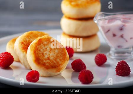 Frittelle di formaggio cottage o scironiki servite con miele e lamponi, vista laterale. Foto Stock