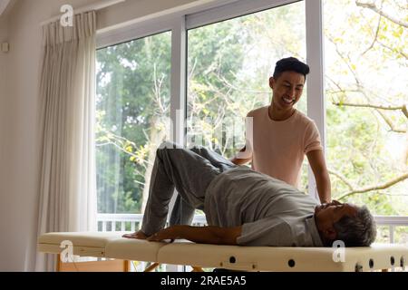 Fisioterapista maschile felice eterogeneo che consiglia e paziente anziano che si esercita Foto Stock