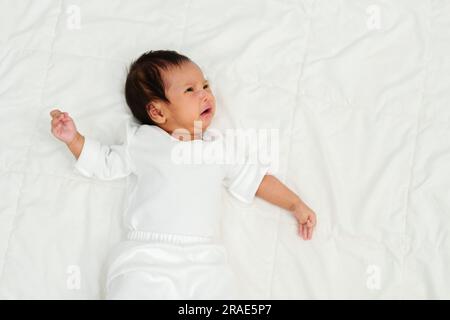 bambino appena nato sdraiato e piangendo su un letto Foto Stock