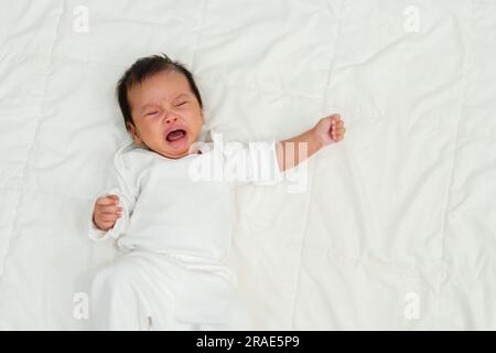 bambino appena nato sdraiato e piangendo su un letto Foto Stock