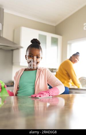 Ritratto di madre e figlia afroamericana felici che puliscono il piano in cucina Foto Stock